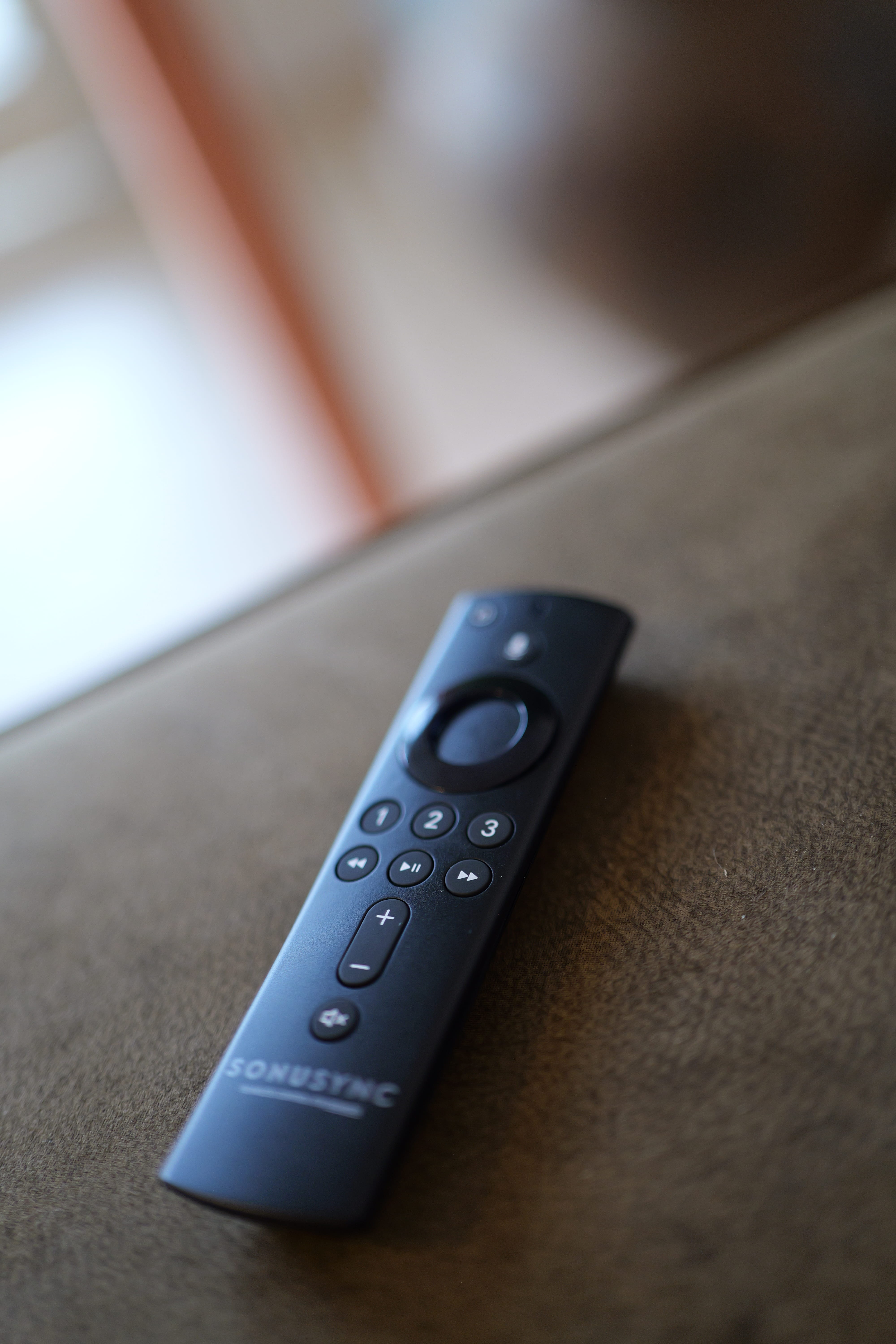 SONUSYNC remote control resting on a couch