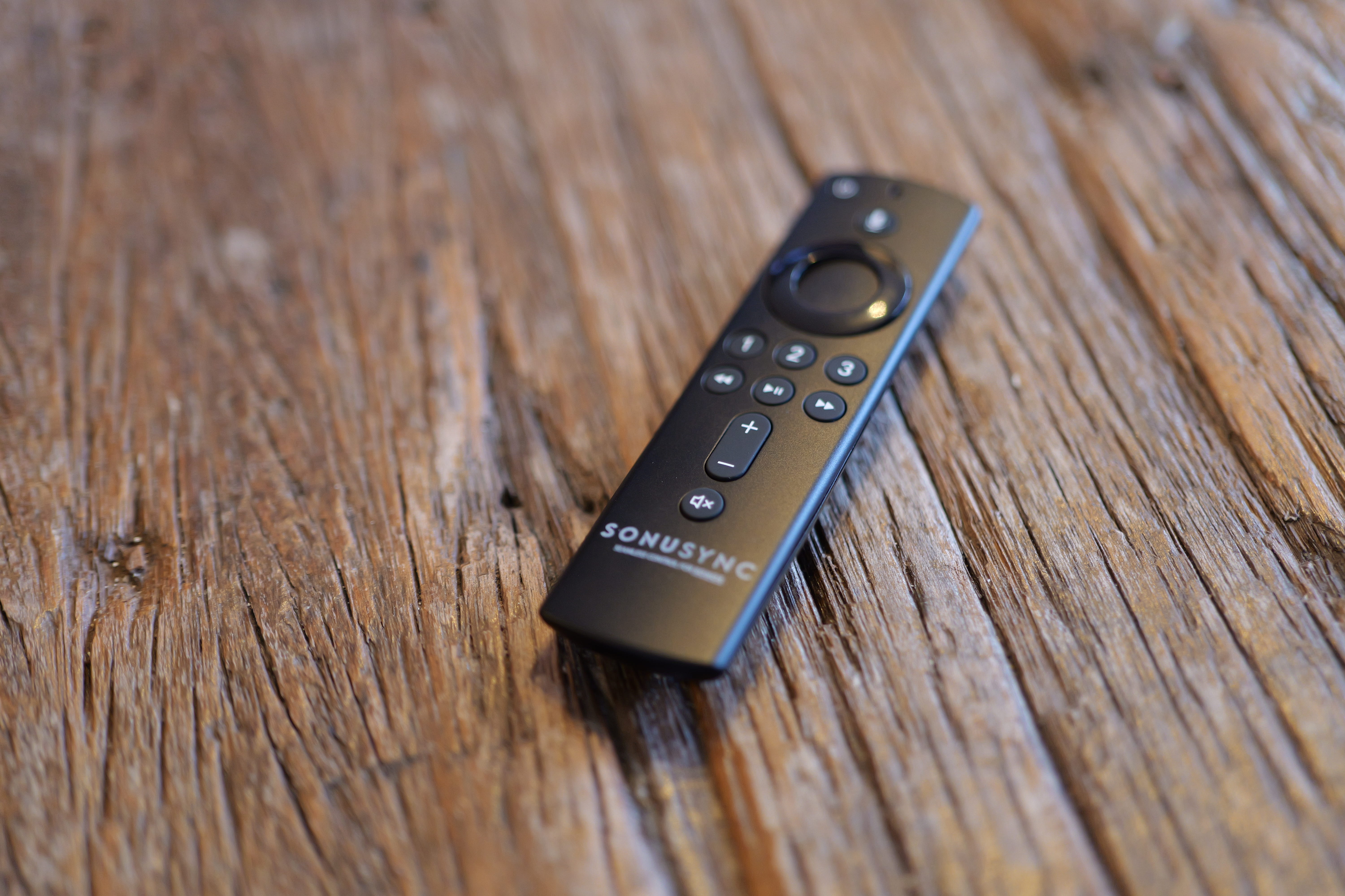 SONUSYNC remote control lying on a wooden surface